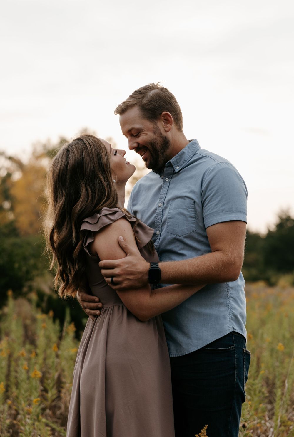 Intimate portrait of couple sharing romantic moment in autumn field at sunset.