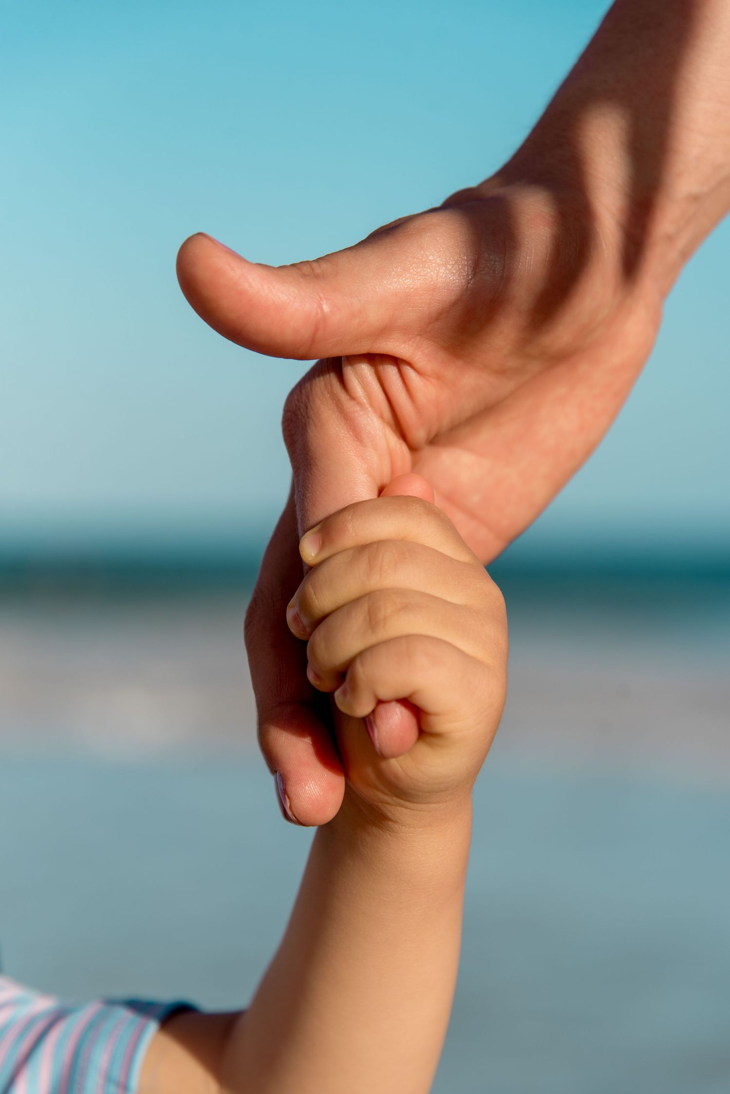 Roberto and his son holding hands with the beach behind them