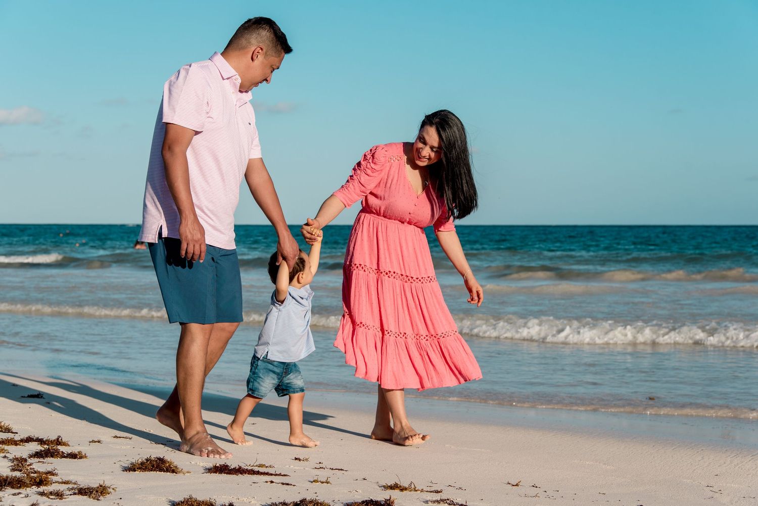 The family walking hand in hand along the shoreline of Tulum's beach