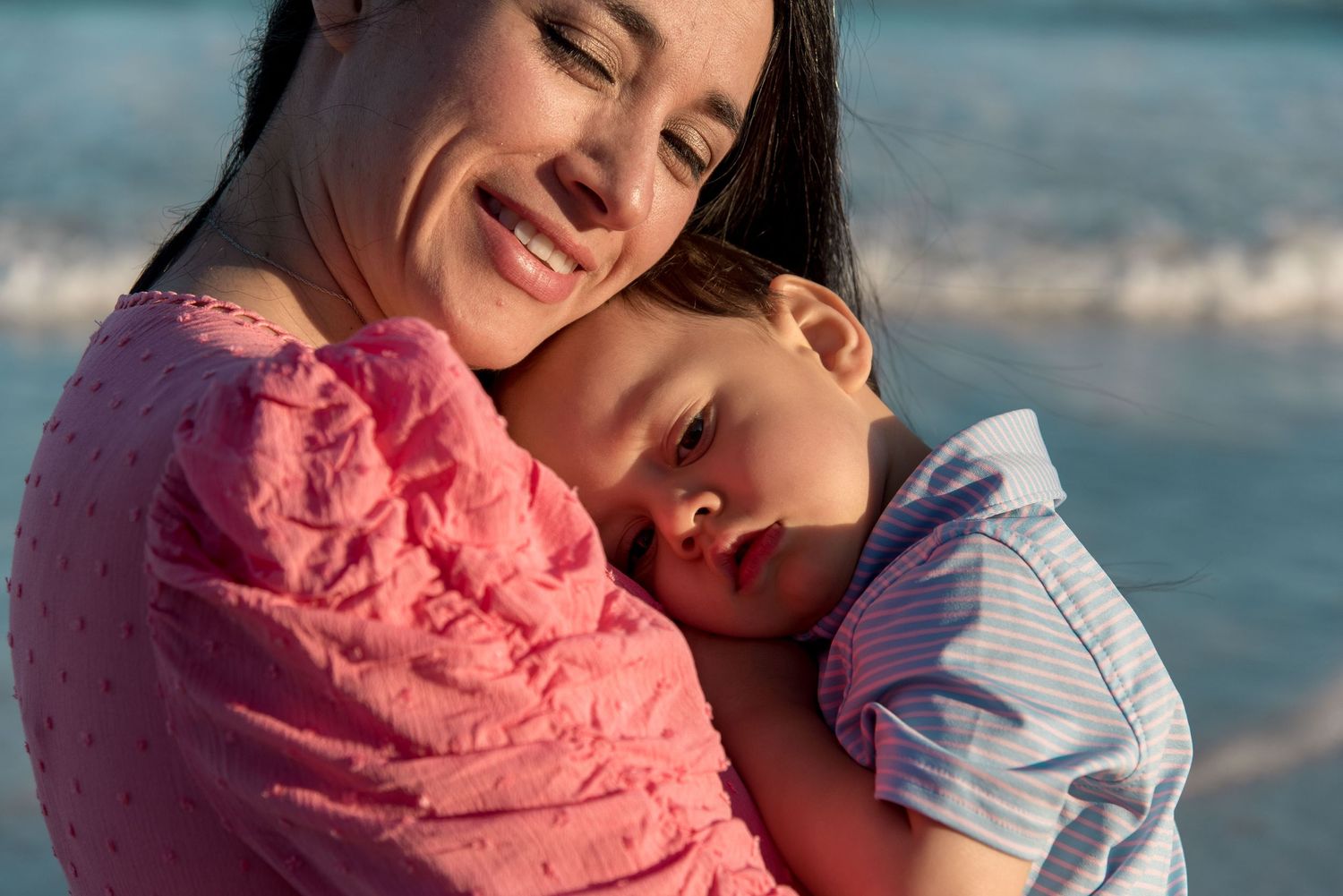 Rodrigo resting on his mother's chest while the waves crash in the background