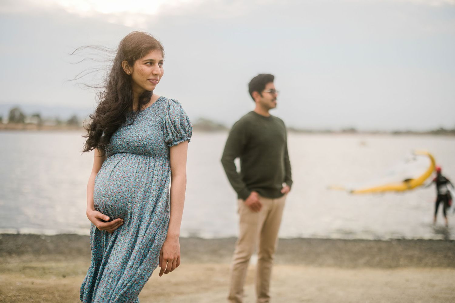 Maternity photoshoot by the water with boats sailing in background.