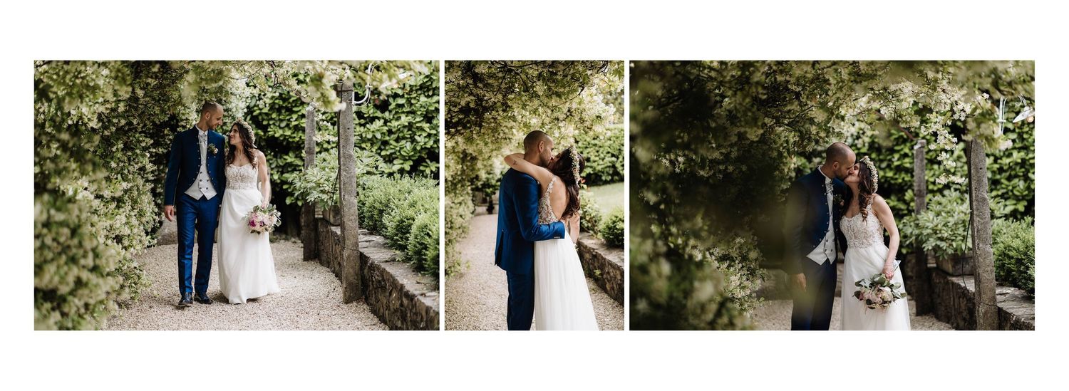 Bride and groom sharing a romantic moment among stone pillars surrounded by lush green garden foliage.