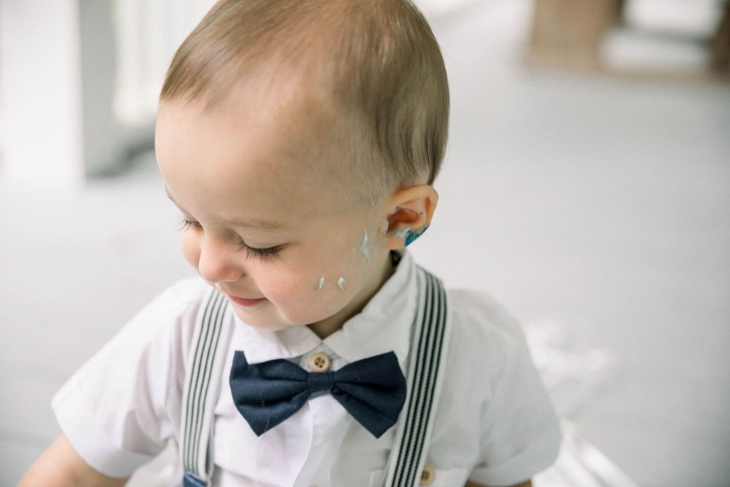 A series of photos showing a baby in formal wear sitting next to a birthday cake.