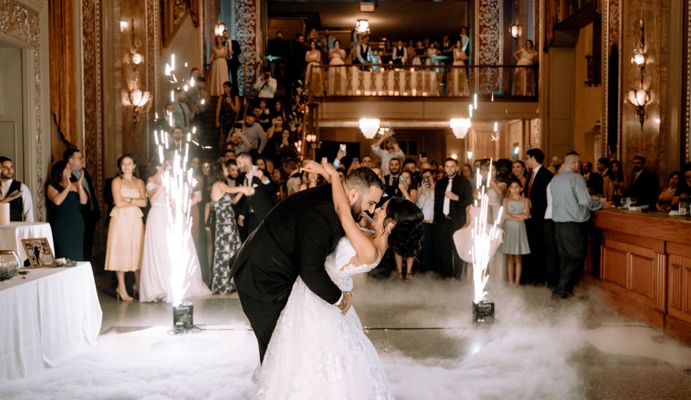A romantic first dance at a wedding reception with the couple dipping dramatically in an elegant ballroom.