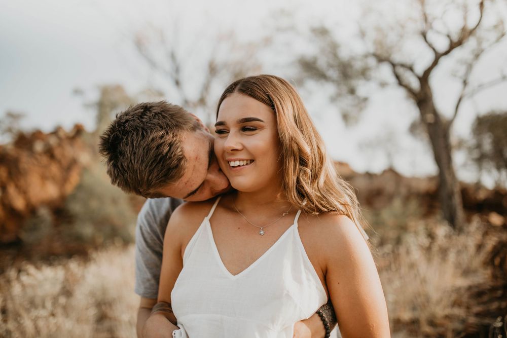 Man kissing woman's neck on hill in Mount Isa