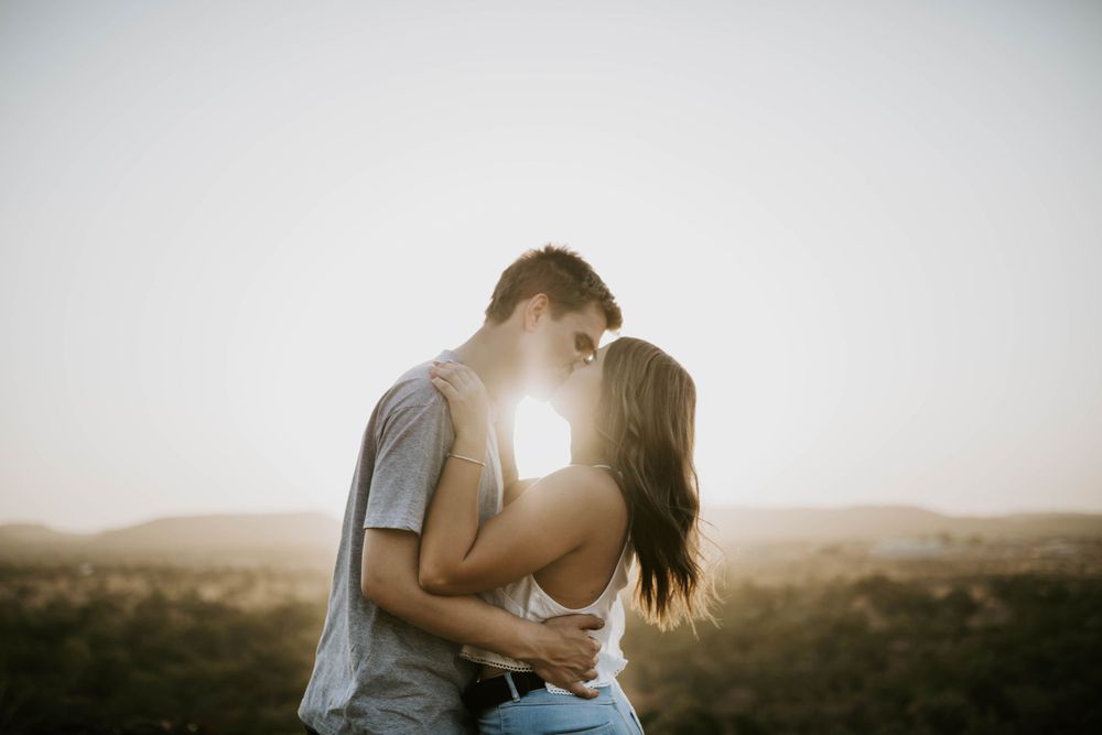 Couple kissing with sunset between them on a hill in Mount Isa