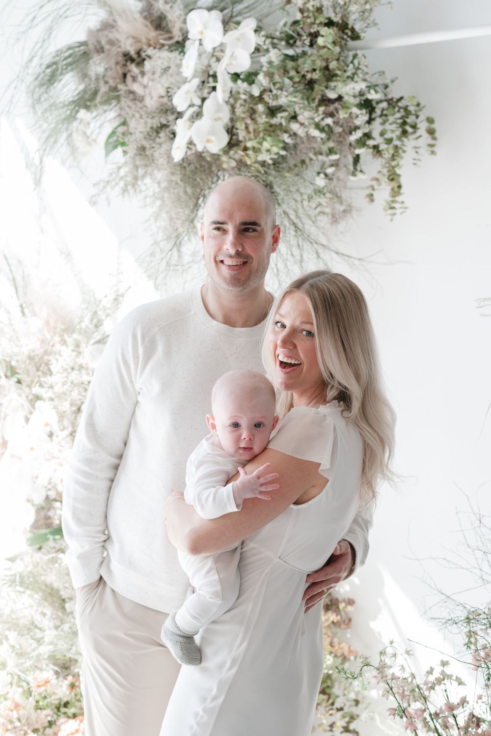Toronto family dressed in all white posing in front of a floral backdrop - elegant and timeless family photography by Jess GC Photography