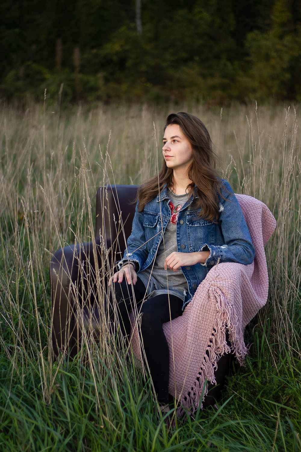 High school senior sitting on a chair in a field