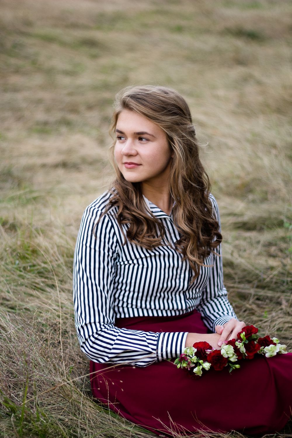 Beautiful high school senior sitting in a field with a flower wreath