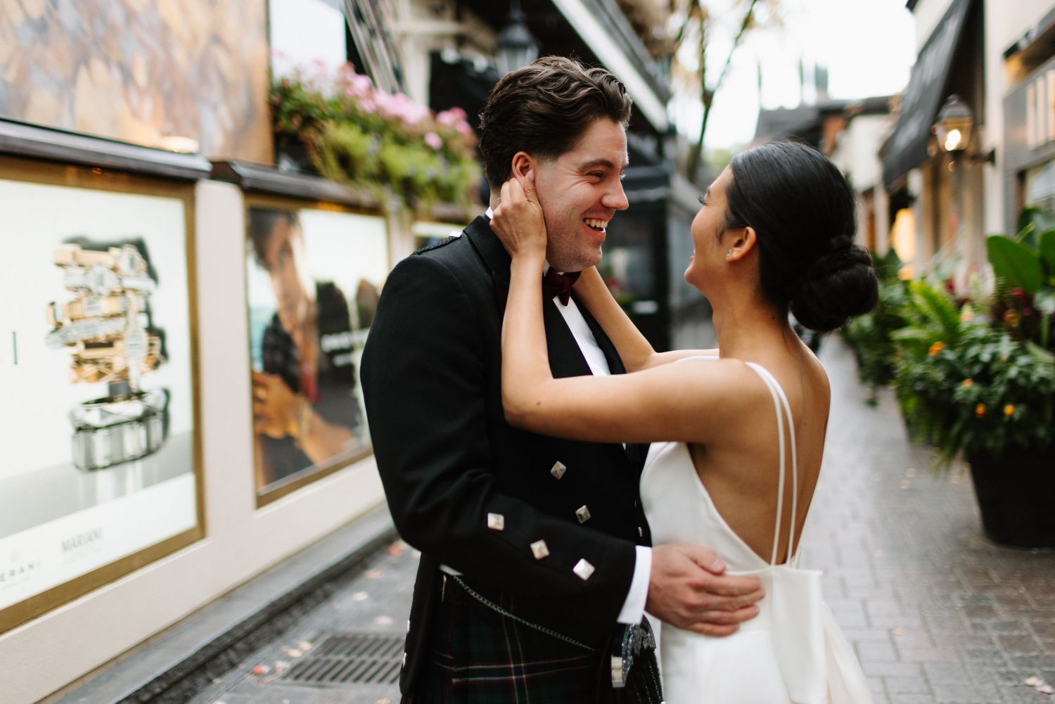 Intimate moment between couple in wedding attire in an urban alleyway.
