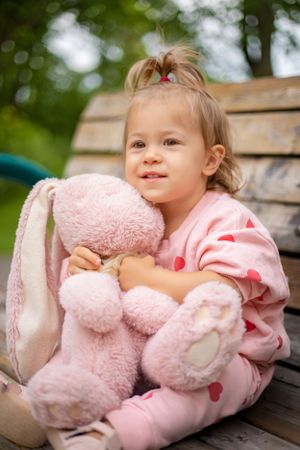 Wooden bench setting with pink hearts and plush toy creates a charming outdoor scene.