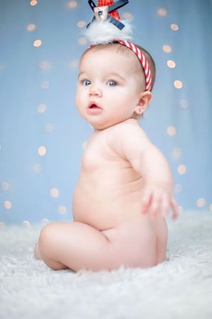 Winter themed portrait with candy cane striped headband against blue bokeh background.