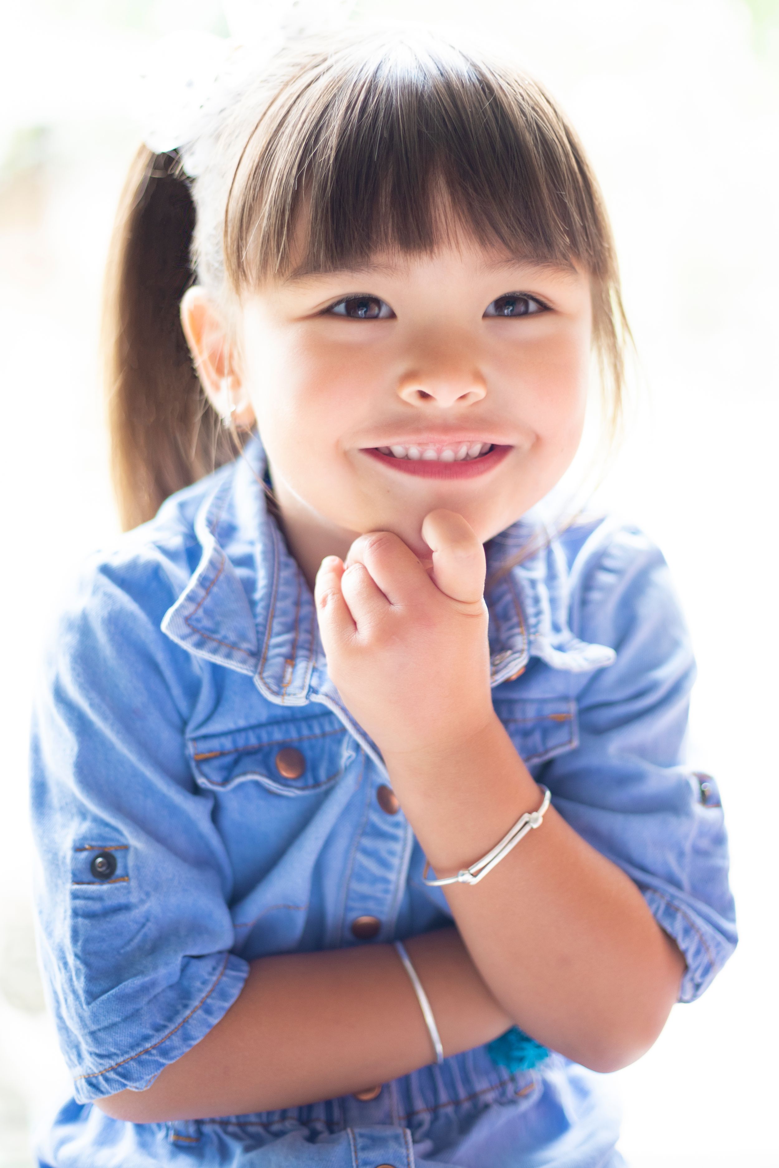 Portrait of a cheerful child in denim clothing with pigtails.