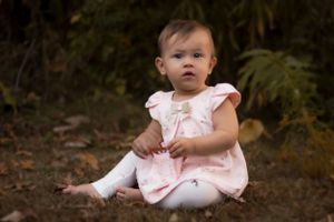 Soft pink dress creates a delicate look against a natural outdoor background.