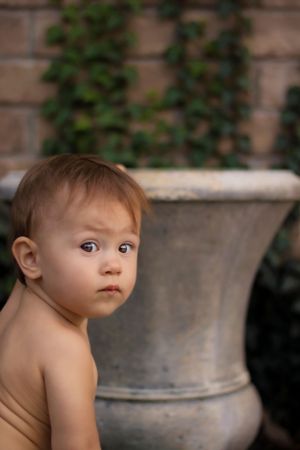 Outdoor portrait with clay pots and greenery creating a natural garden backdrop.