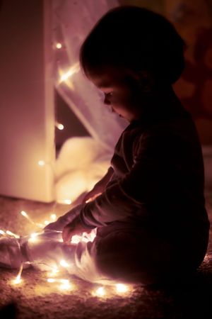 String lights create a magical glow in the darkness, casting soft illumination in a cozy indoor setting.