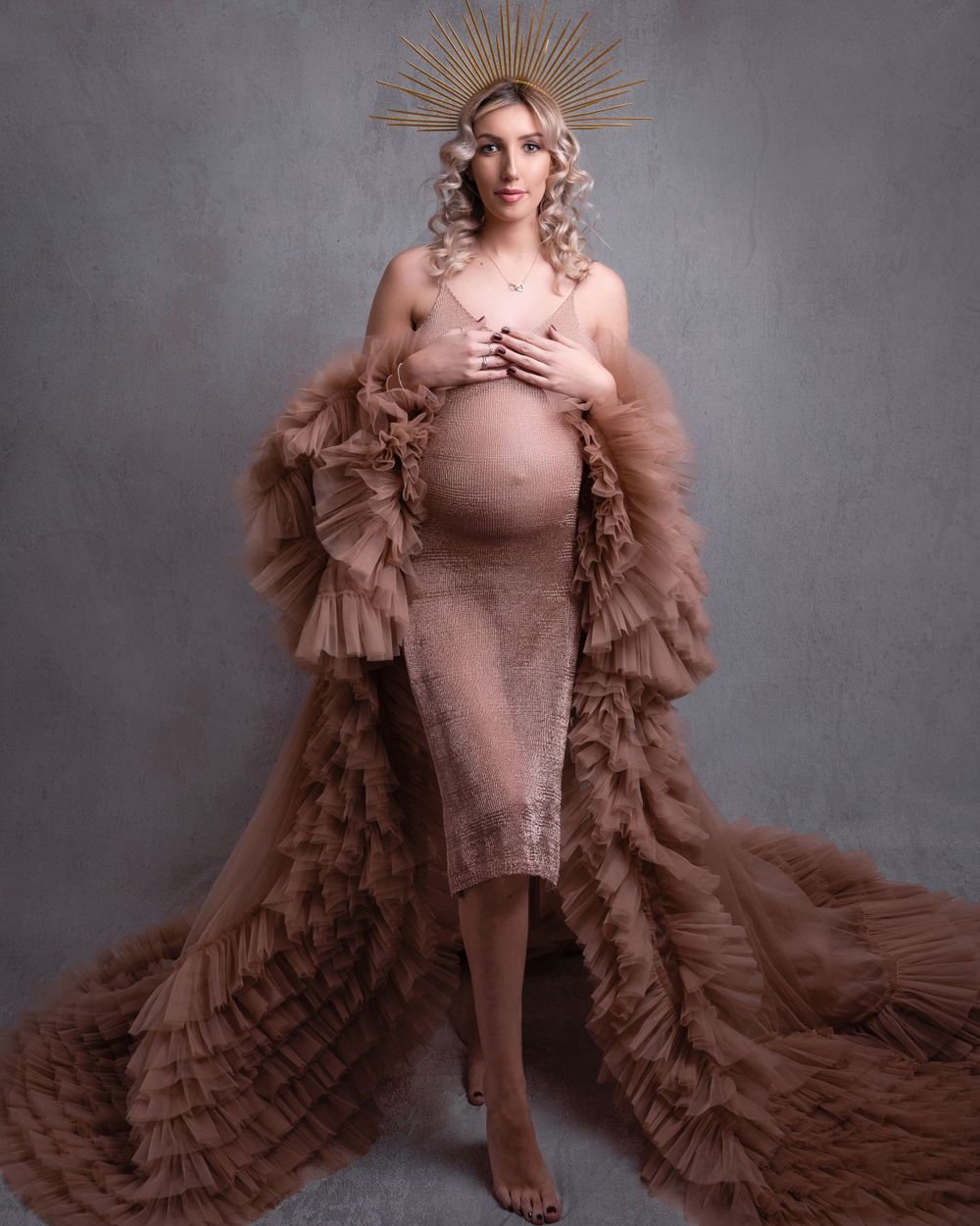 Maternity portrait in dusty rose ruffled gown with dramatic sunburst crown headpiece.