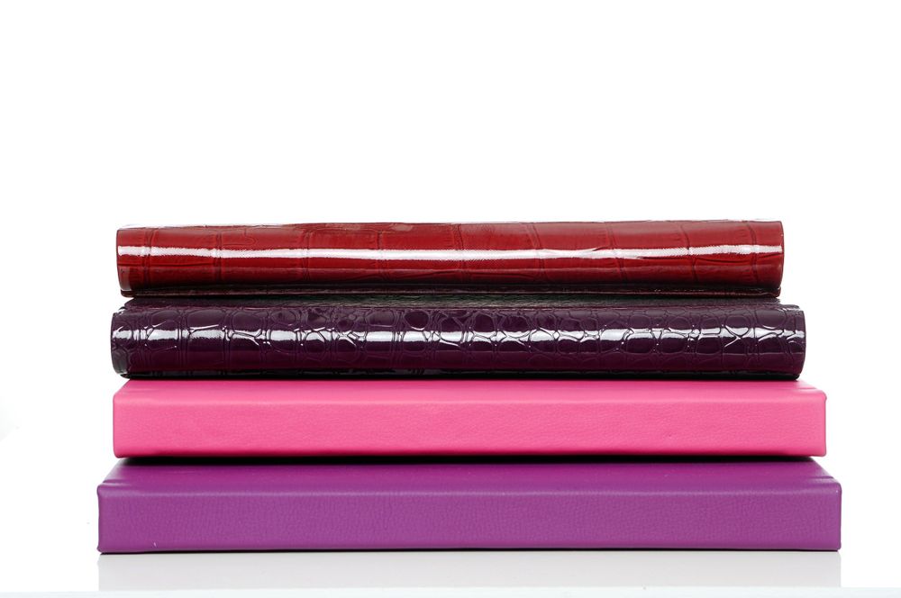 A stack of colorful hardcover books in shades of red, purple, and pink arranged horizontally.