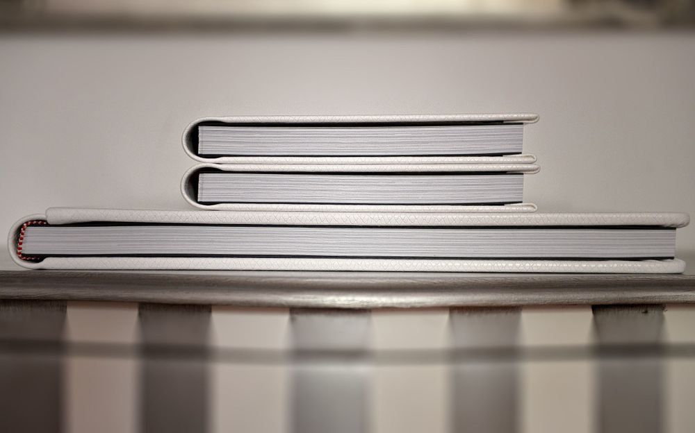 Minimalist black and white macro shot of book spines stacked on a reflective surface with shallow depth of field.