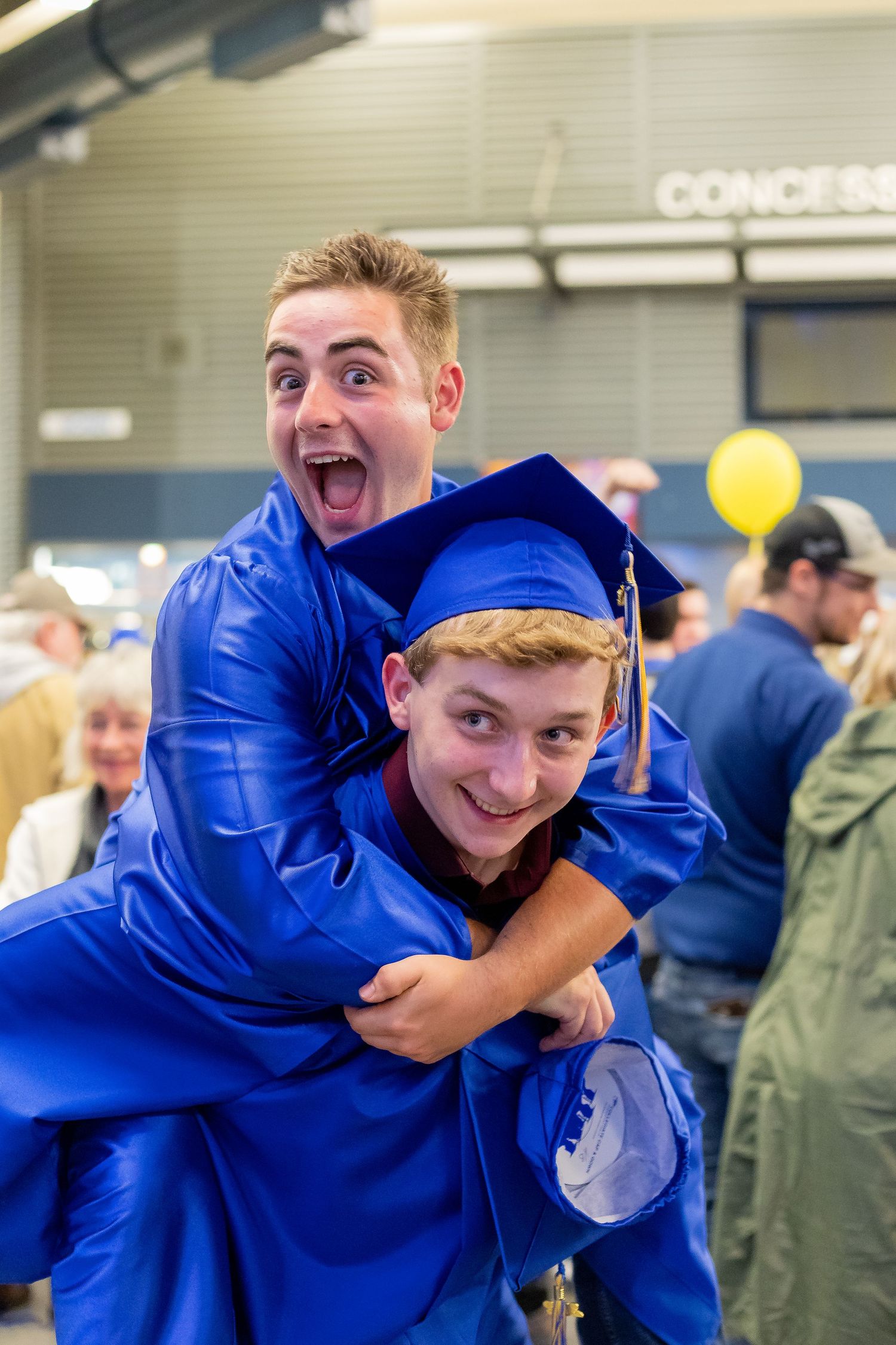 Graduates in bright blue robes share an excited celebratory moment with animated expressions.