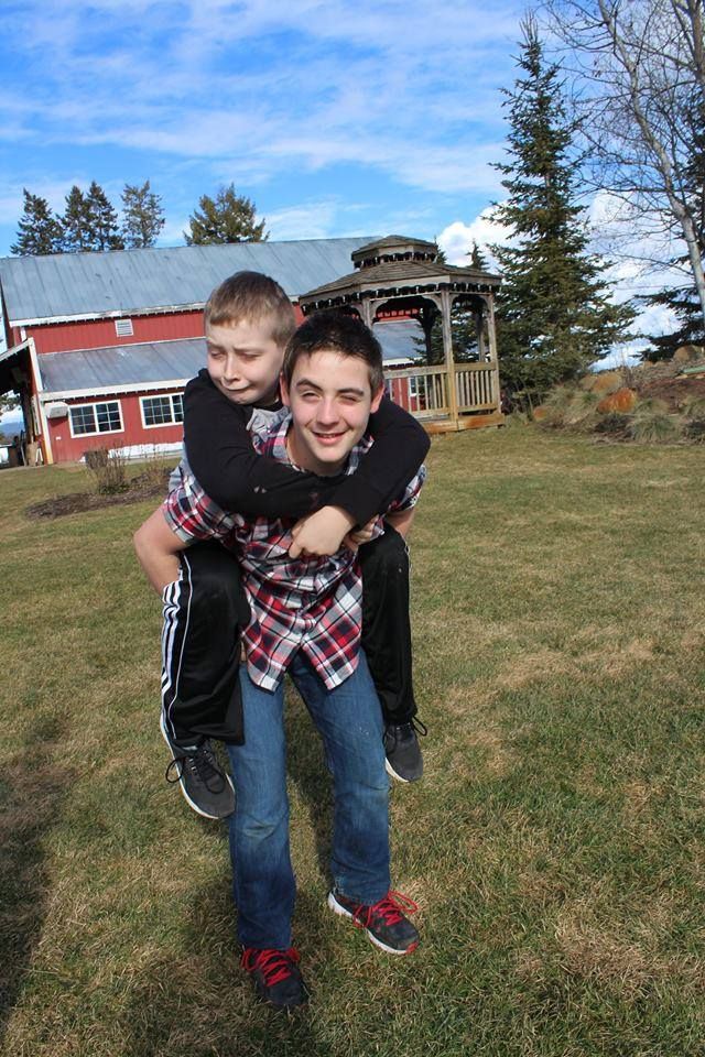 Piggyback ride in front of a red barn and gazebo on a sunny day.
