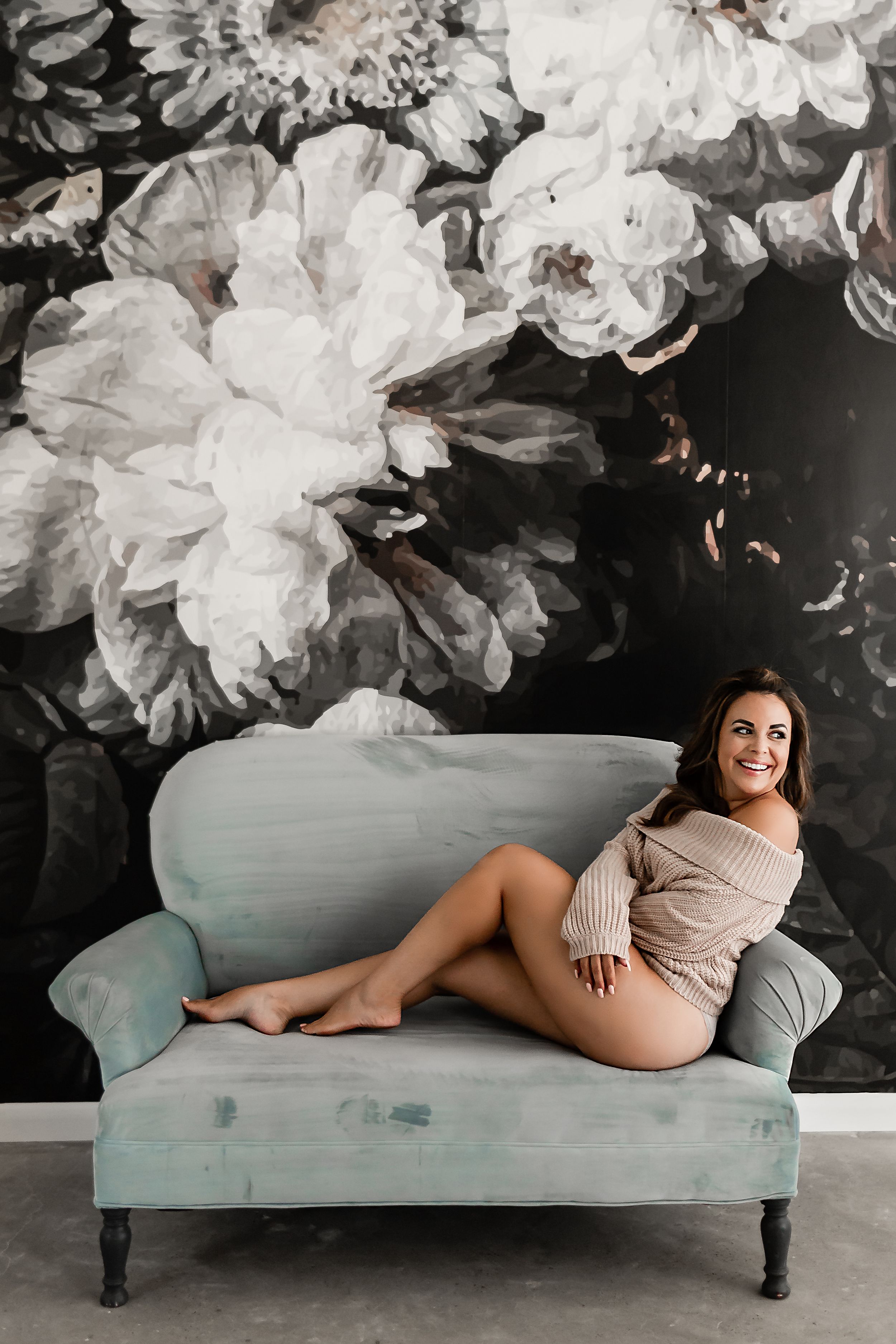 Carrie poses on a soft blue couch for her boudoir session at The Oak Atelier in Conroe, TX.