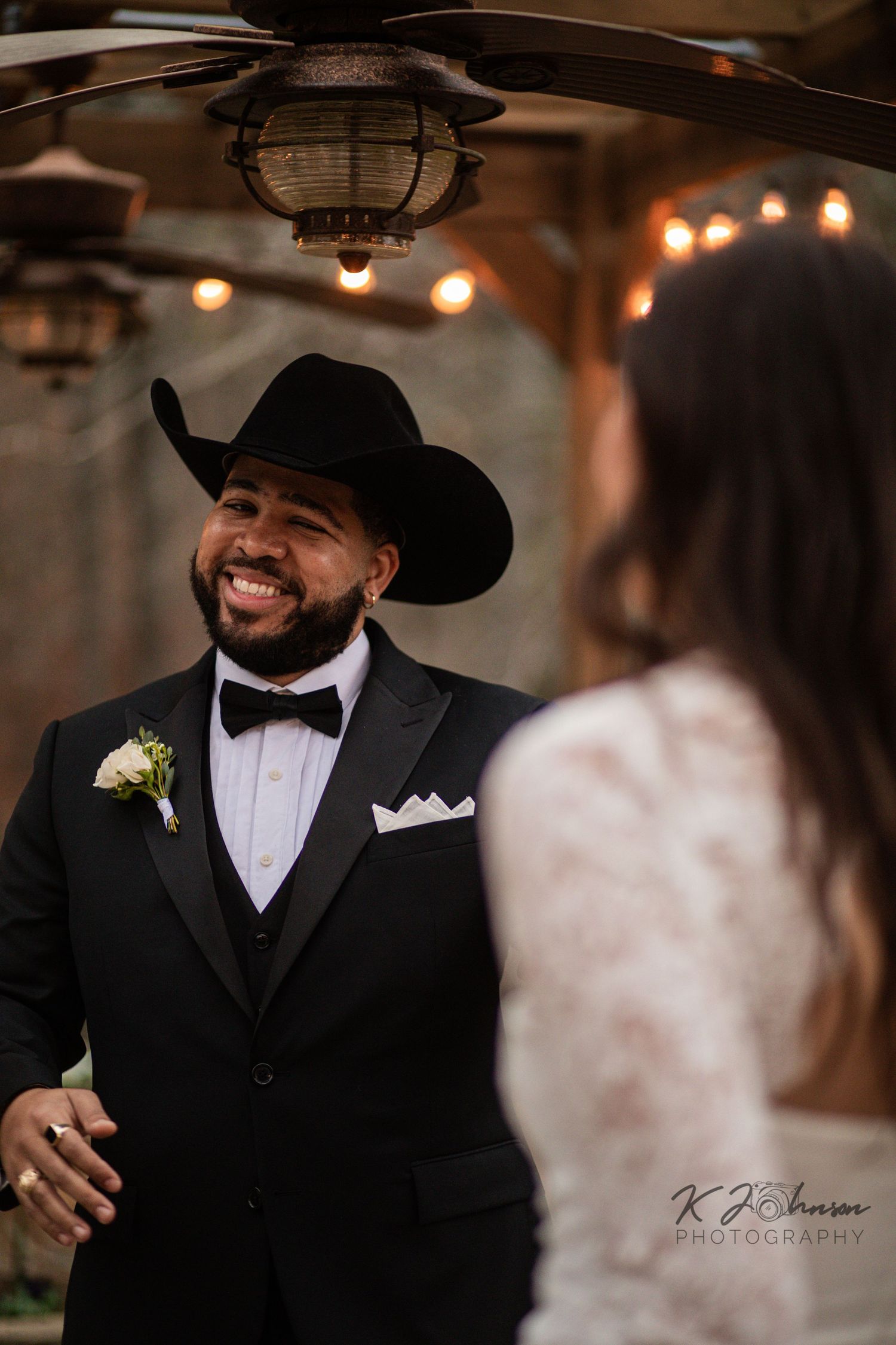 Formal wedding reception in rustic barn venue with hanging string lights creating warm ambiance.