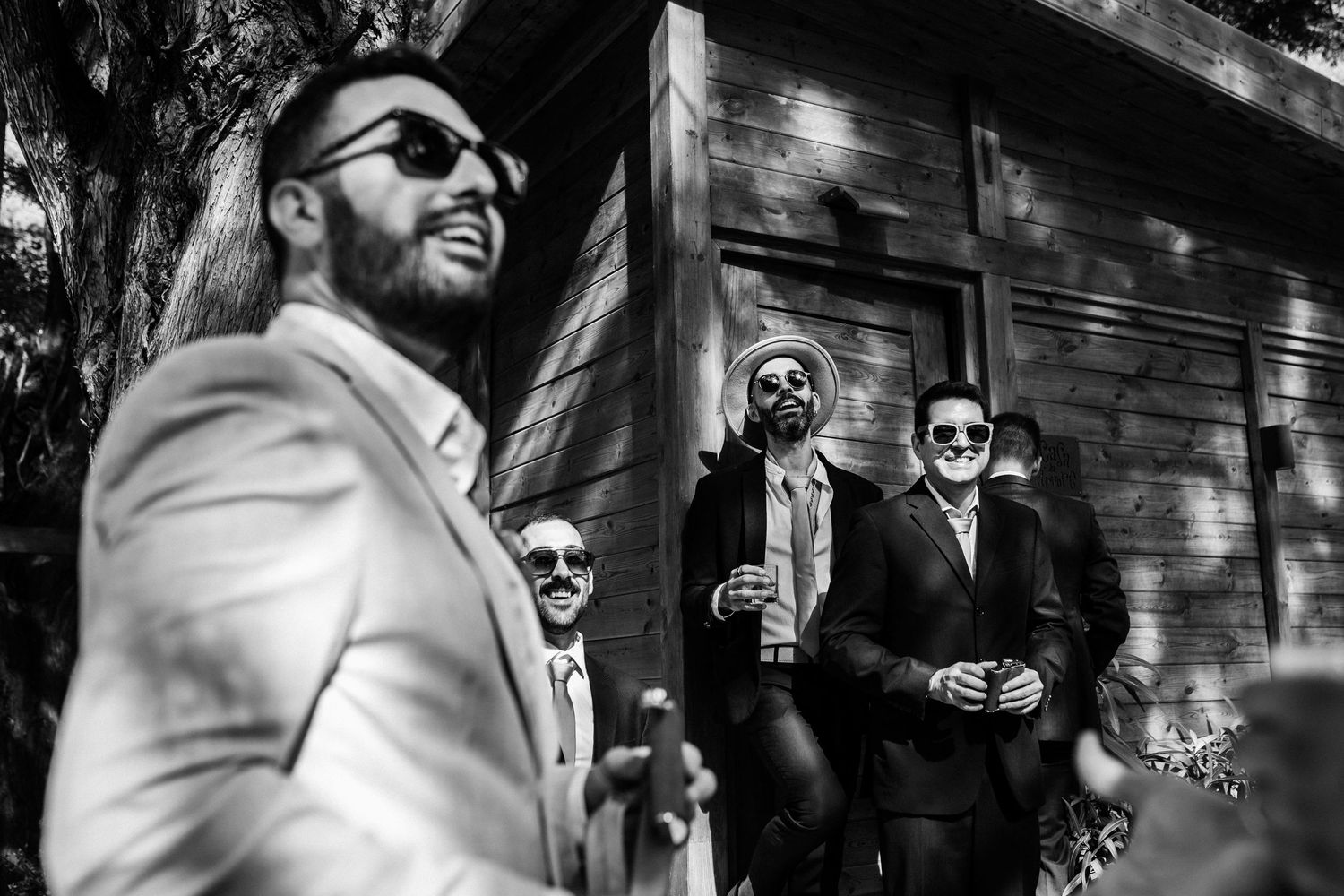 Black and white photo of stylishly dressed men in sunglasses standing outside a building in dramatic lighting at Quinta da Bichinha