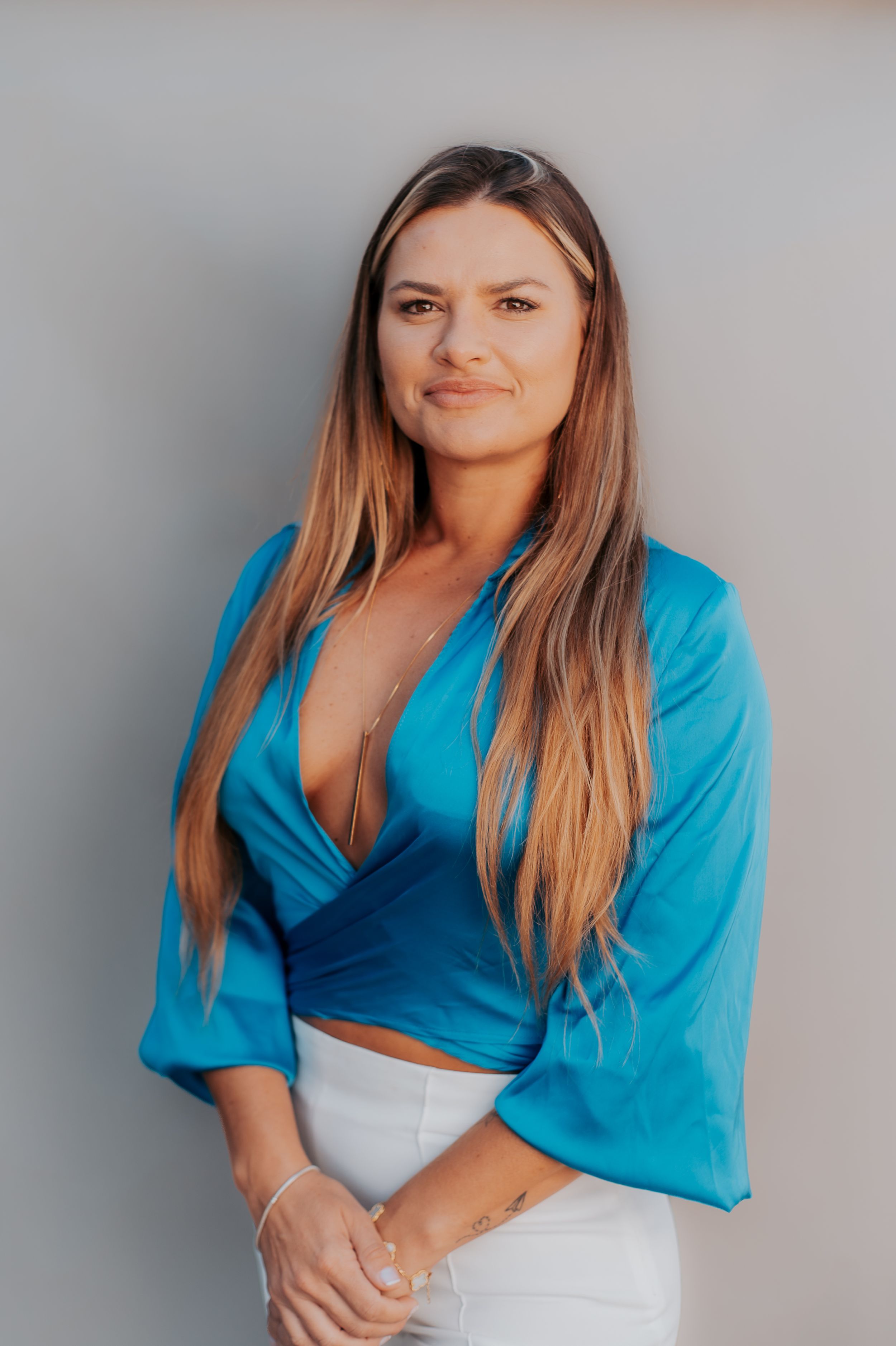 Portrait of a woman in bright blue wrap top against neutral background.