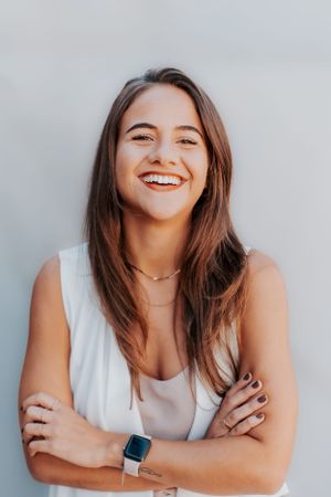 Candid portrait of a woman in white tank top wearing smartwatch and necklace.