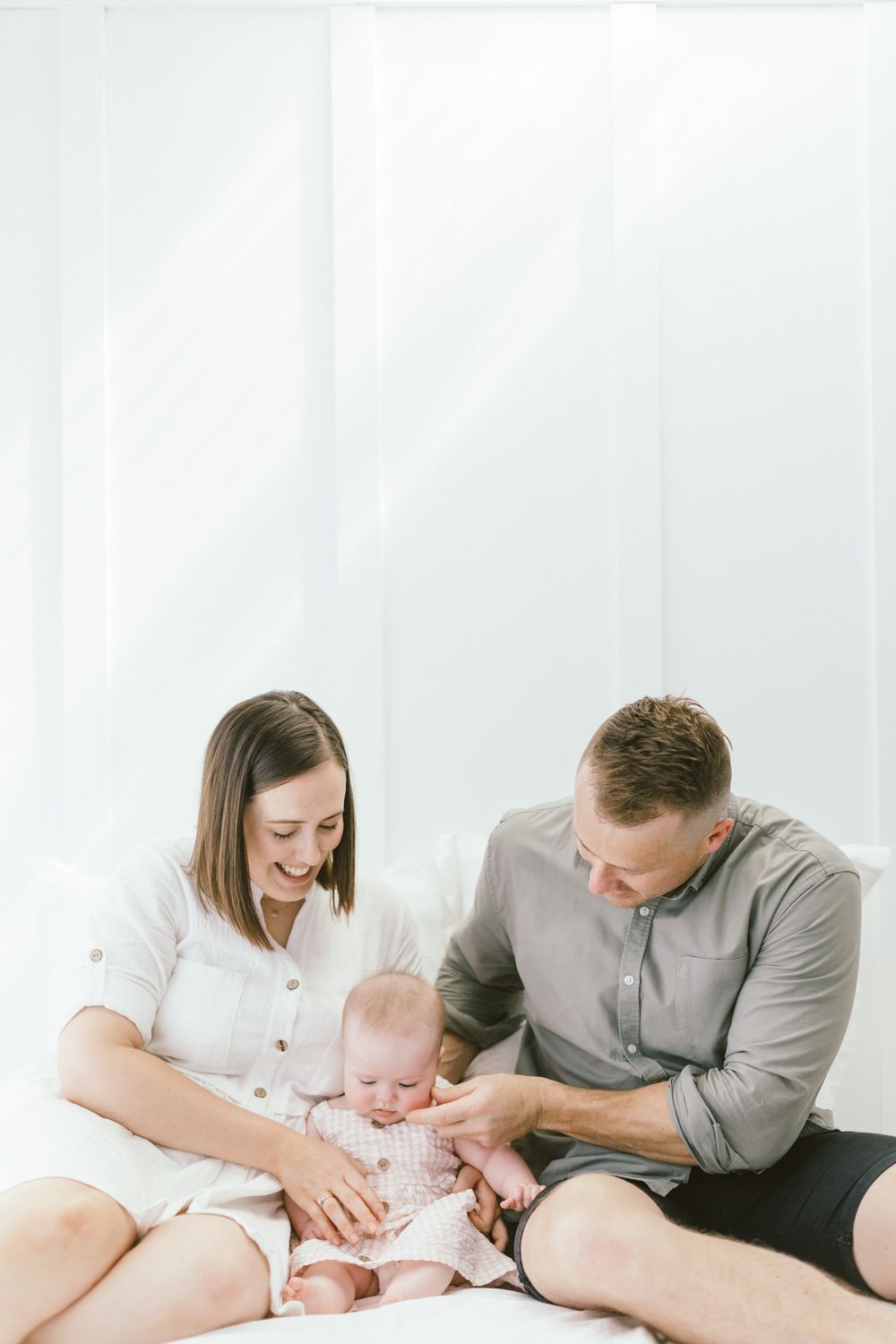 Intimate family portrait showing tender moment against white backdrop.