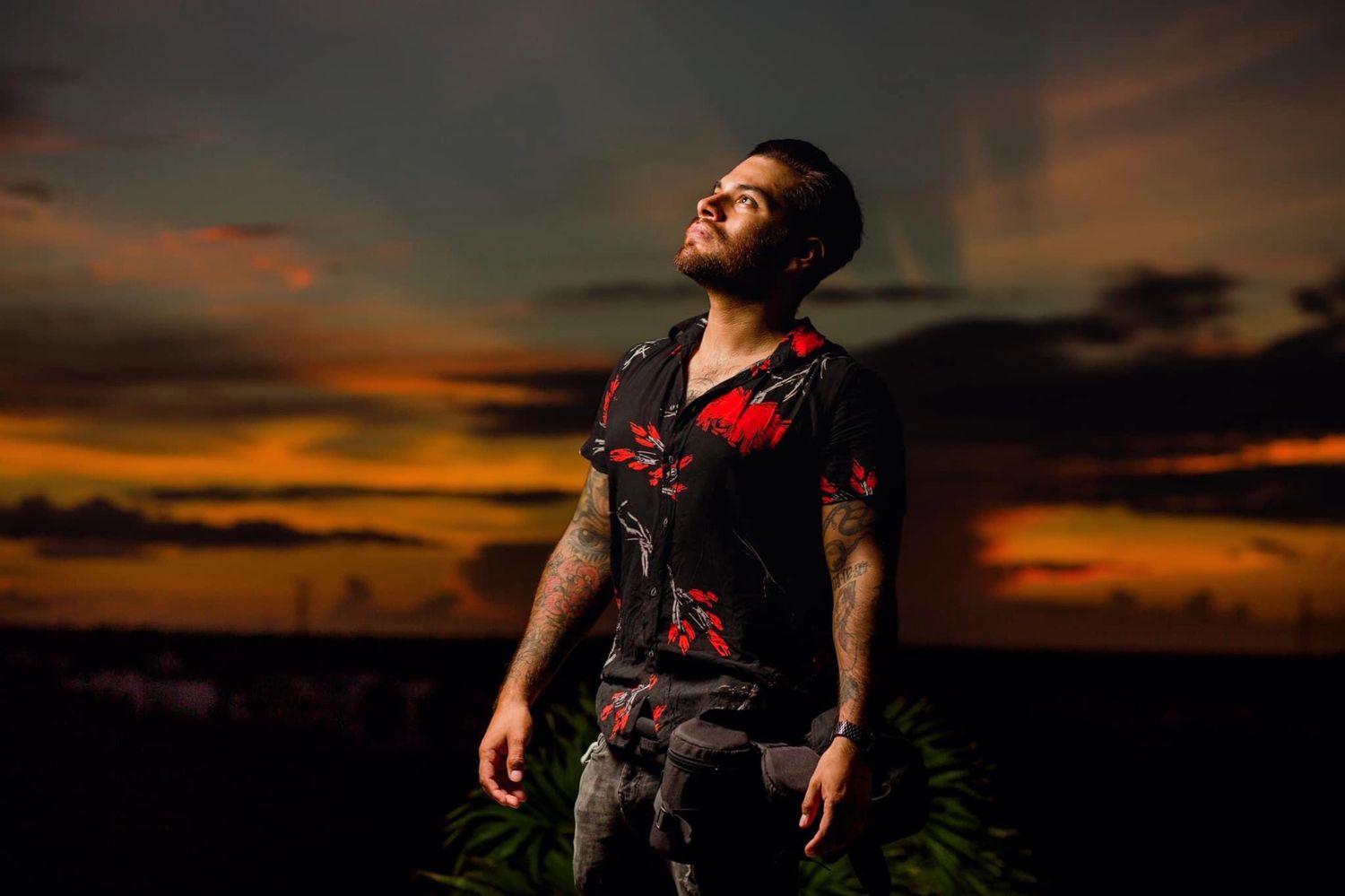 Dramatic portrait against vibrant sunset sky with orange and purple clouds.