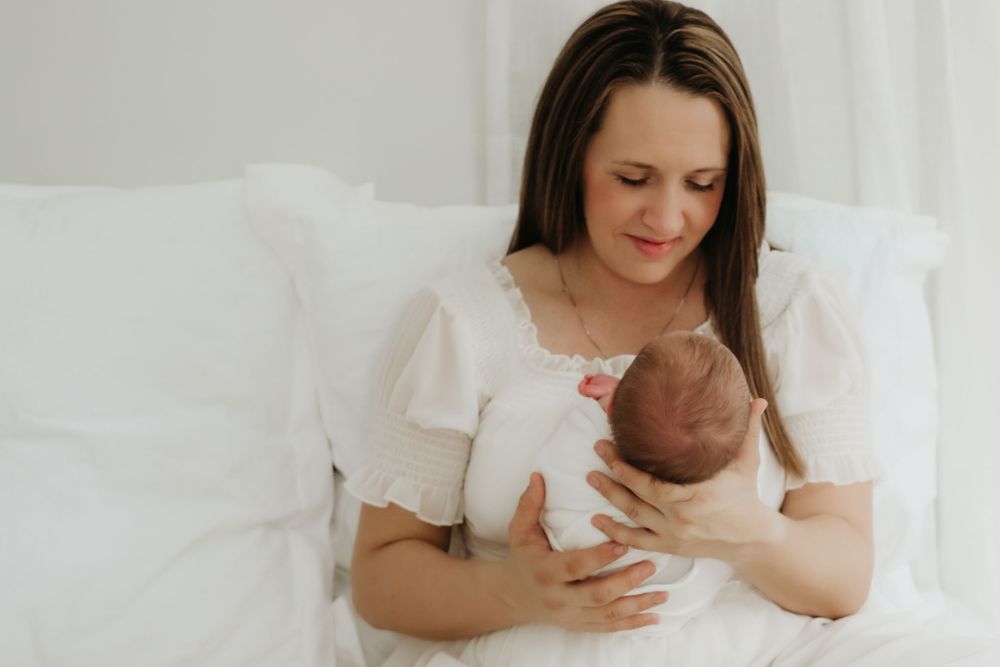 Gentle nurturing moment as parent cradles newborn baby dressed in white.