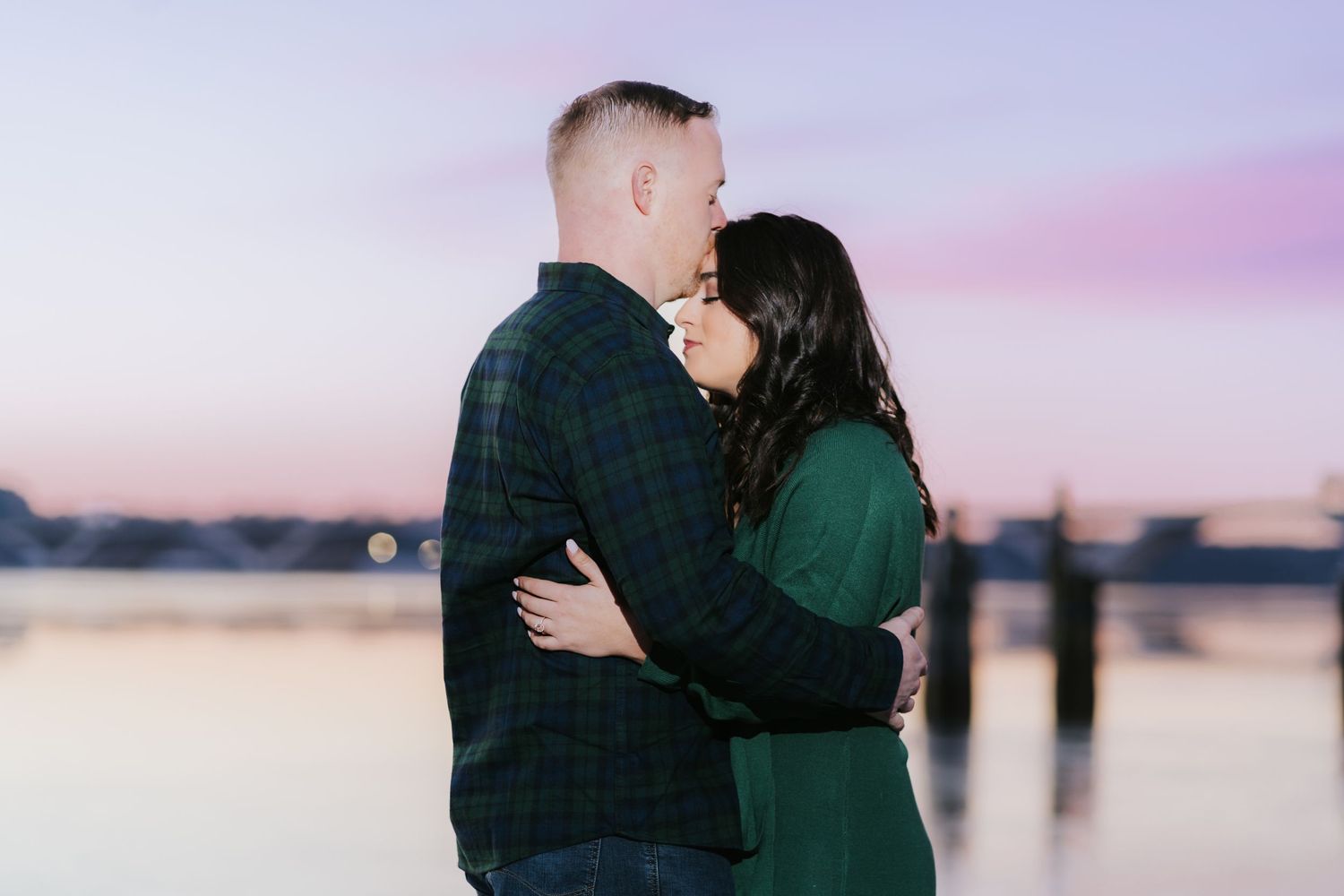 Silhouetted couple embracing during sunset by waterfront.