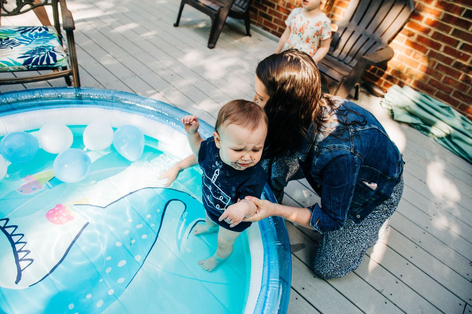 A one year old getting cleaned off in a baby pool from his cake