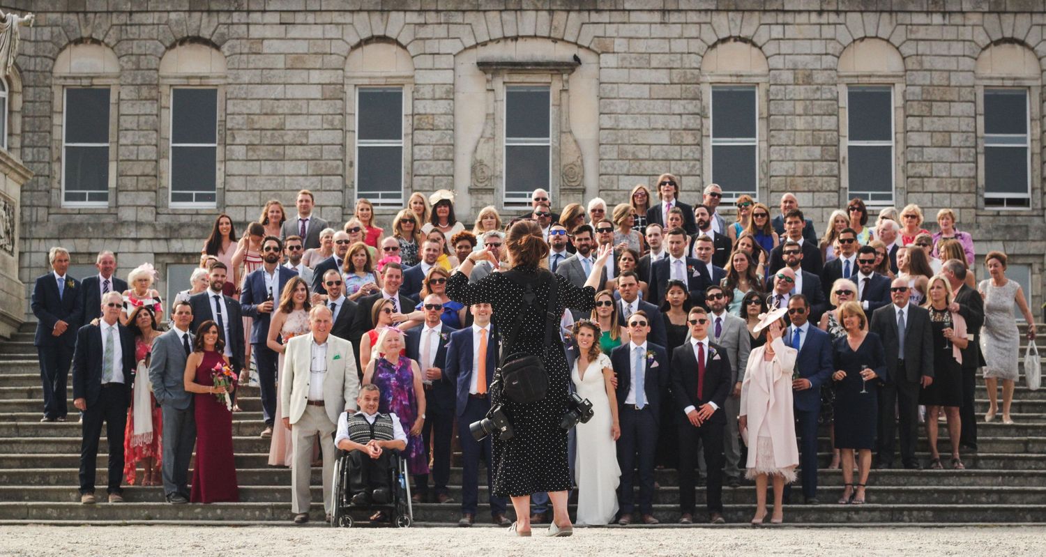 Large group wedding photo on stone building steps.