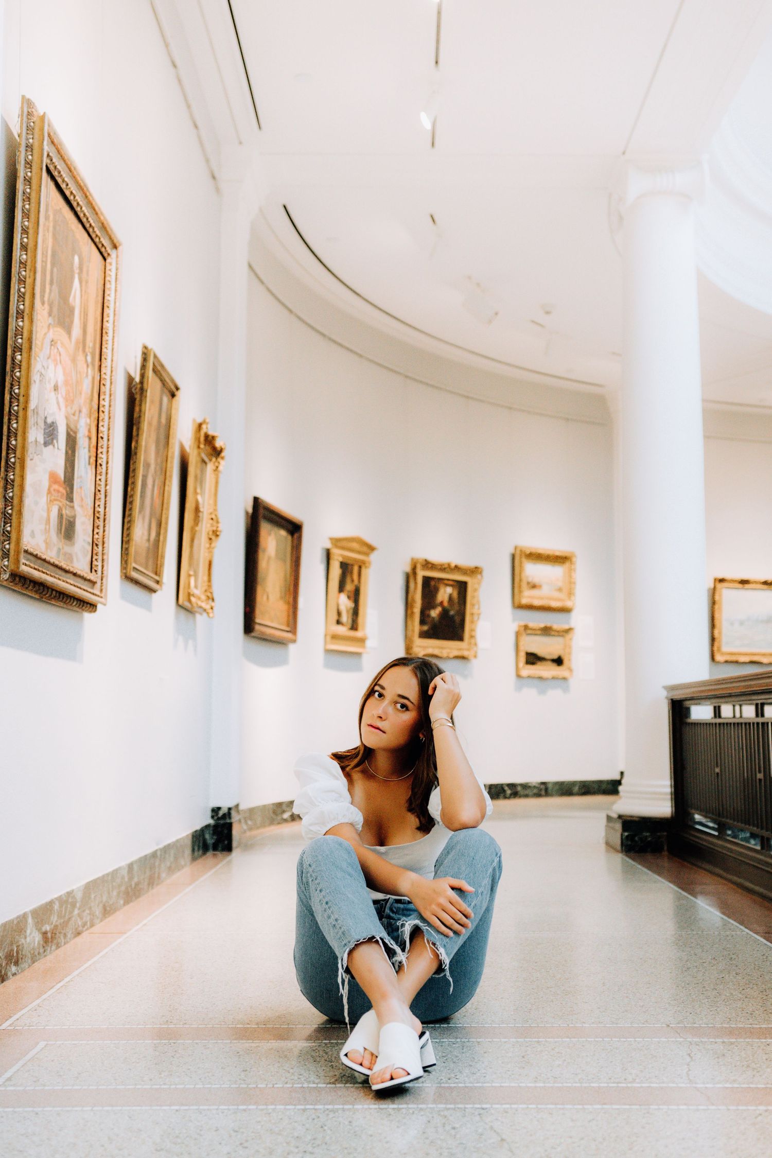 Casual portrait inside art gallery with white walls and gilded frames.