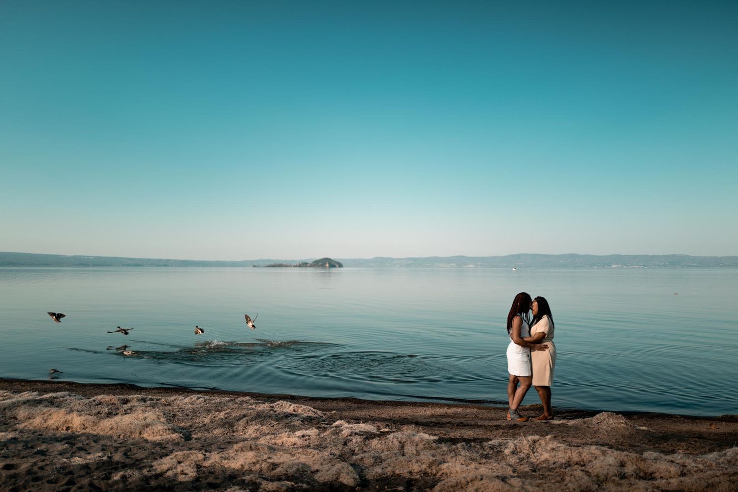 Glückliches Paar bei einem romantischen LGBTQ+ Engagement Shooting am Ufer des Bolsenasees in Italien