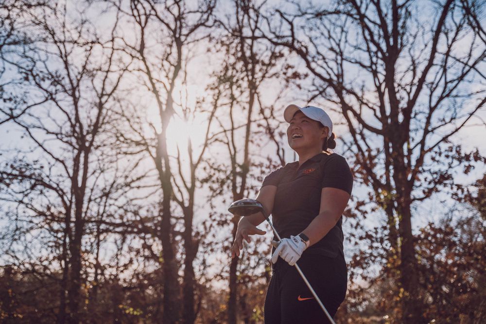 Athlete silhouetted against sunlight through bare trees in an autumn scene.