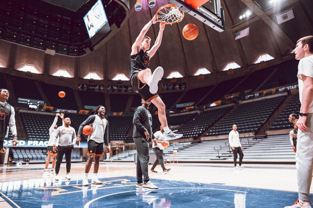 Basketball players practicing aerial moves and dunks during team workout session.