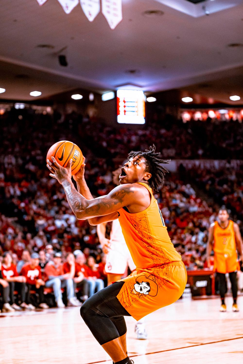 Basketball player in orange uniform goes up for a layup during game action.