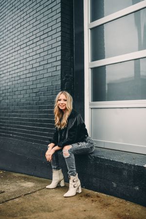 Street style photography against grey brick wall with modern architectural elements.