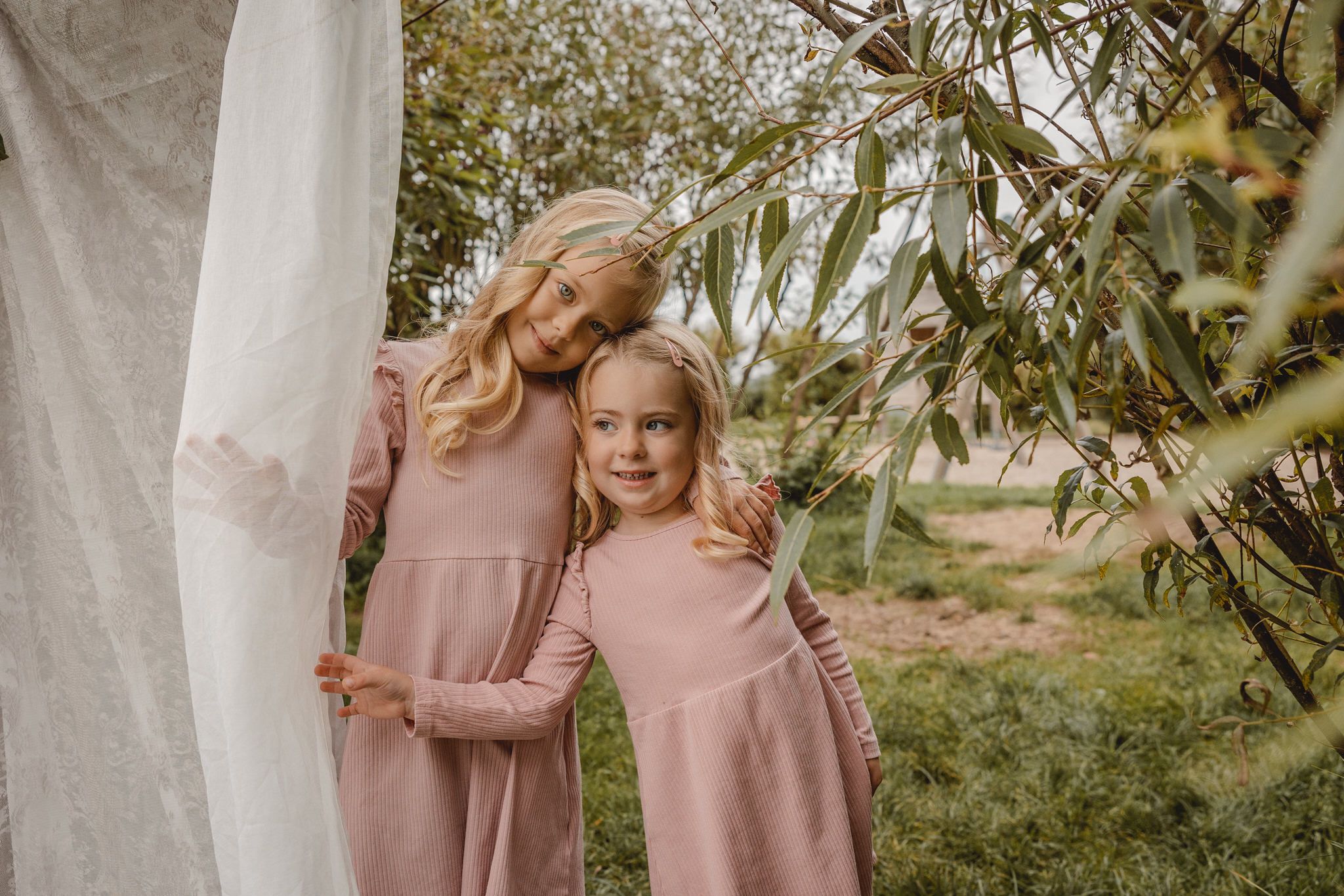 Sweet candid moments captured between family members in matching pink outfits outdoors.