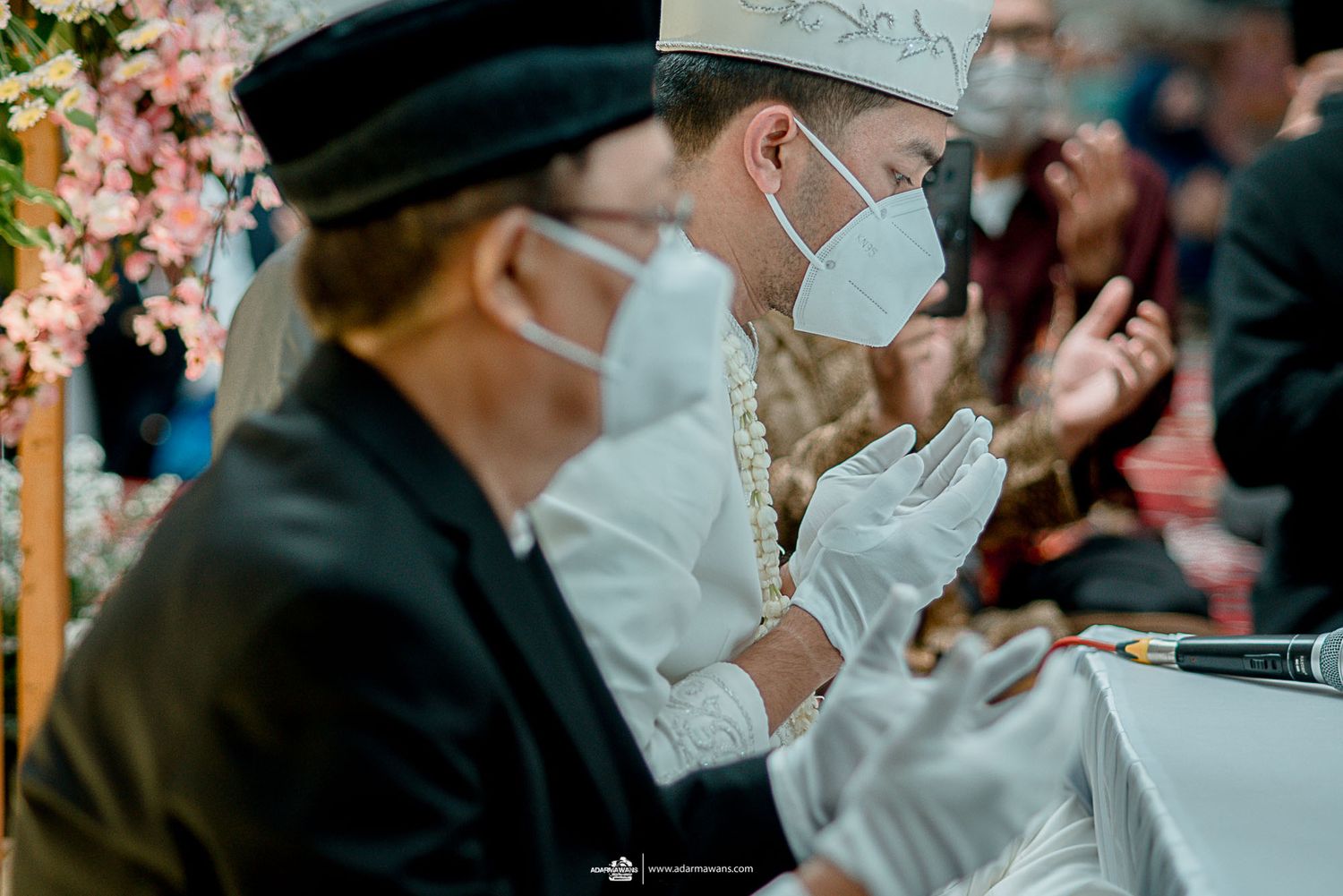 Ceremony participants in traditional headwear and masks during solemn moment.