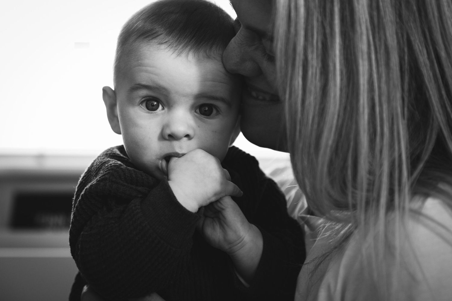 Black and white portrait of small child with finger in mouth.