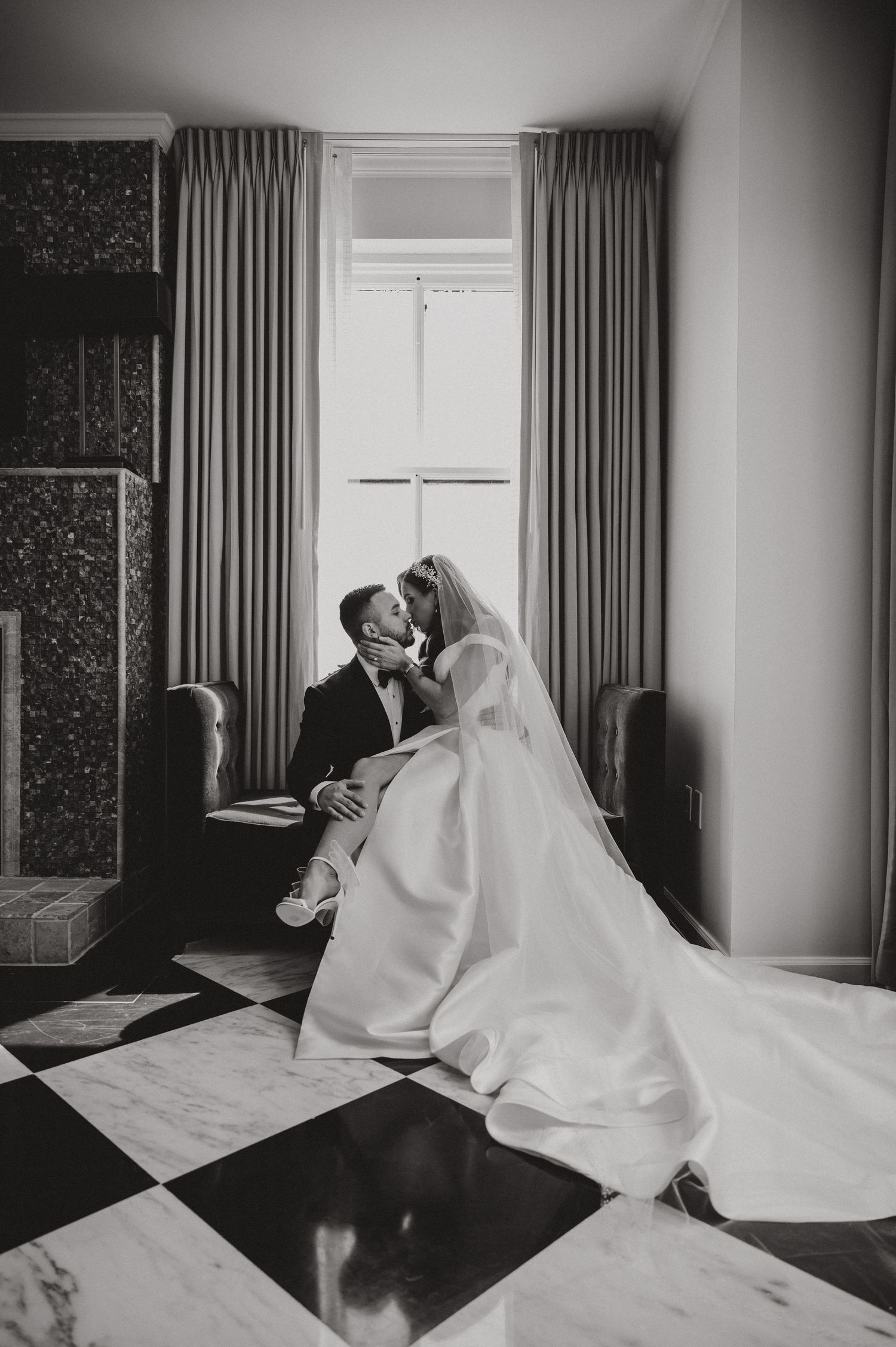 An intimate black and white portrait in an elegant room with checkered floors.