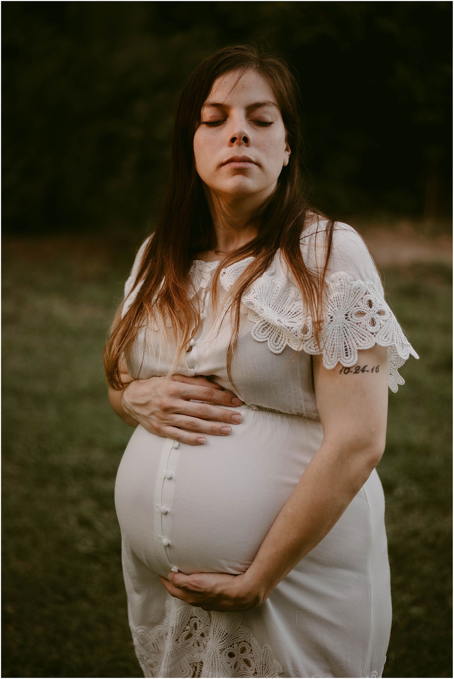 Intimate maternity close-up showcasing delicate lace sleeve details and gentle lighting.