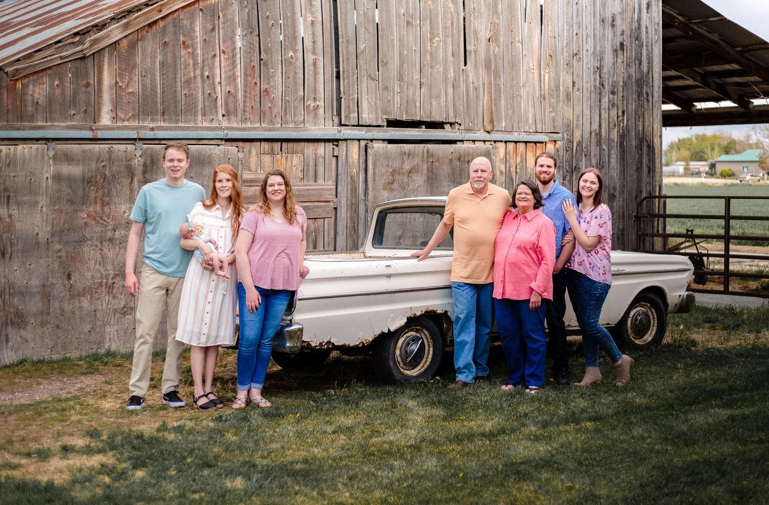 family with grandparents and children posing in front of an old ford and rustic barn