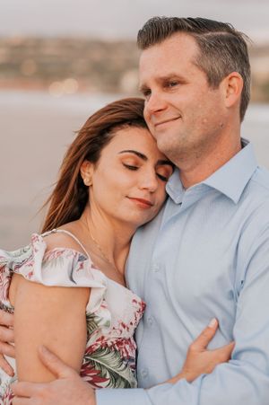 Sweet candid moments captured of couple in soft lighting against coastal backdrop.