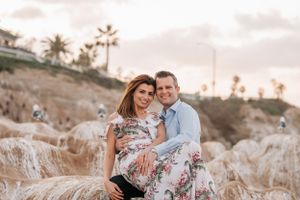 Sunset engagement portraits on coastal cliffs with palm trees in background.